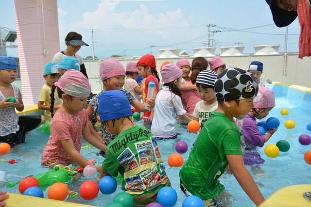 園児たちがプールに入っているボールやおもちゃでなどで遊んでいる写真